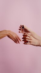 Women apply moisturizing lotion to their hands with a dropper, vertical video, close-up of female...