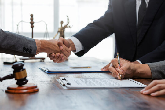 Legal professionals completing a deal, clients signing documents with a lawyer negotiating terms, symbolizing justice and agreement