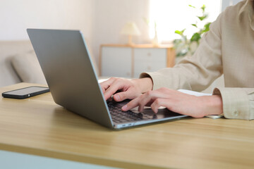 Hands typing on a laptop, a person working or studying from home, connecting online for remote business activities