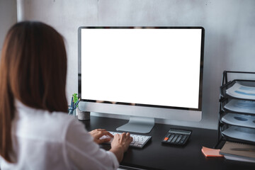 Woman typing on blank screen computer creating a mockup display for website, app, or software promotion at office desk