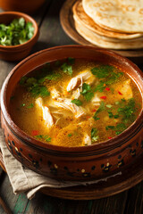 A steaming bowl of Guatemalan kak�ik turkey soup with aromatic spices, fresh cilantro, and a side of warm tortillas.