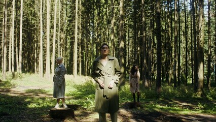 Three women of different nationalities pose standing in the forest on stumps