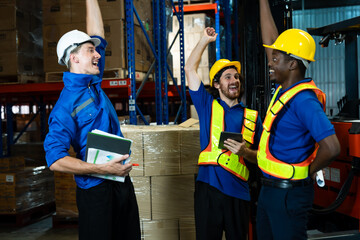 Multicultural team of three male warehouse workers raising arms cheering happily after successful...