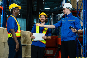 Multiracial male warehouse workers and supervisor sharing happy conversation during logistics planning surrounded by boxes showing cooperative team spirit at industrial distribution warehouse © Ekkasit A Siam