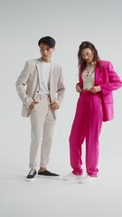 Obraz premium Bright man and woman posing on white background, vertical video