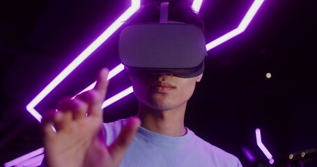 Man in virtual reality headset playing online video game in VR studio