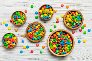 Fototapeta premium different colored round candy in bowl and jars. Top view of large variety sweets and candies with copy space