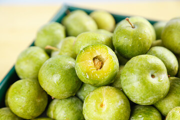 Obraz premium Fresh Green Sichuan Plums - Crisp Healthy Fruits in Container