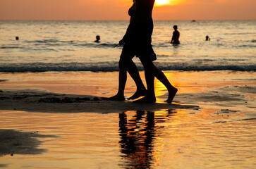 A woman and a man walk on the beach