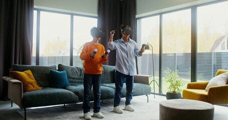 Mother and son in virtual reality headsets playing video game at home