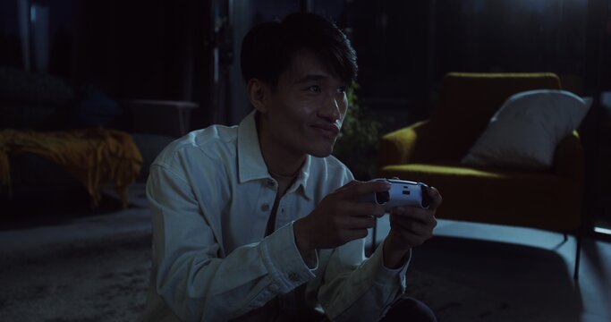 Young man playing video games at home in the evening - Powered by Adobe