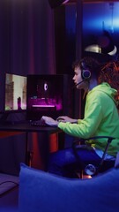 Young man in headphones playing video games on the computer
