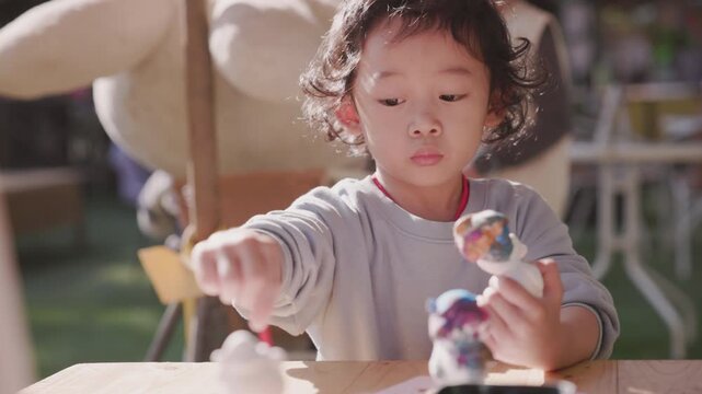 Child carefully coloring a plaster sculpture with a paintbrush, enjoying a creative DIY craft project that develops imagination, focus, artistic expression, fine motor skills, and creativity.
