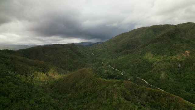 Hicming, Virac, Catanduanes, Philippines - Rolling Green Hills and a Winding Road Stretch Beneath Brooding Clouds - Aerial Drone Shot