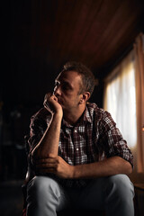 Man with headache, depression, sadness and loneliness sitting on a chair at home.