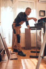 Carpenter working and assembling furniture in a new apartment.