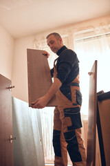 Carpenter working and assembling furniture in a new apartment.