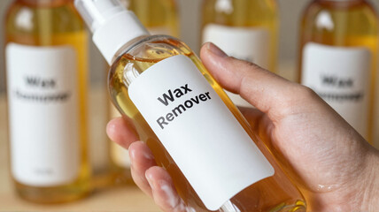 Hand holding bottle of wax remover in studio