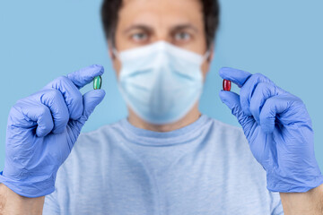 Doctor hands taking medicine capsule pills on blue background. a red and green pill in a doctor hand.