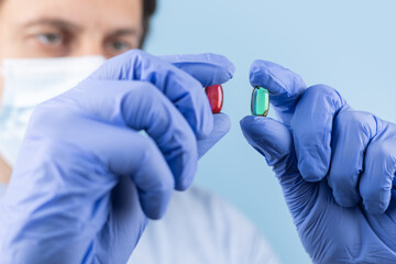 Doctor hands taking medicine capsule pills on blue background. a red and green pill in a doctor hand.