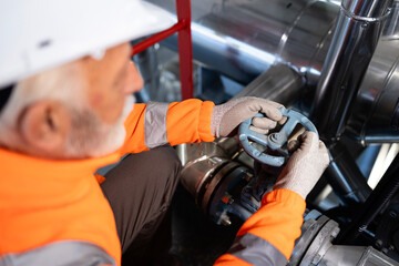 Worker wearing safety vest operating plant valve