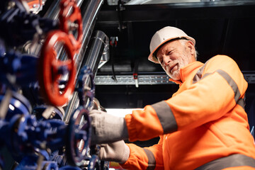 Senior engineer experiencing back pain working on industrial equipment