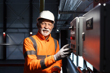 Senior electrician working at industrial control panel