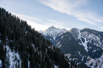 High altitude mountain landscape in winter. Perspective of a snowy road leading to rocky peaks and summits