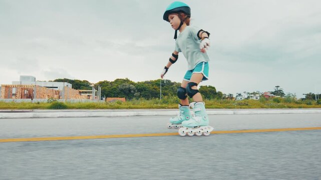Girl learns roller skating on the road in the park and does her first attempts in the sport