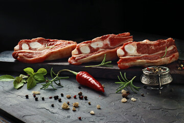 Raw Lamb Chops with Fresh Herbs, Chili Pepper, and Spices on Dark Slate