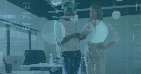 Reviewing two women colleagues in business attire studying handheld device at office, data overlays