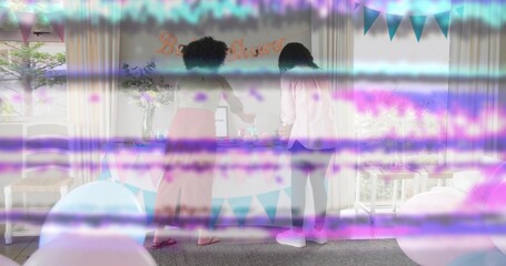 Decorating two women arranging pastel table at home, placing cake and balloons, purple or blue bands