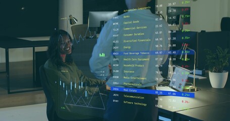 Pointing standing man showing AR financial overlay to seated woman in blazer at office, copy space