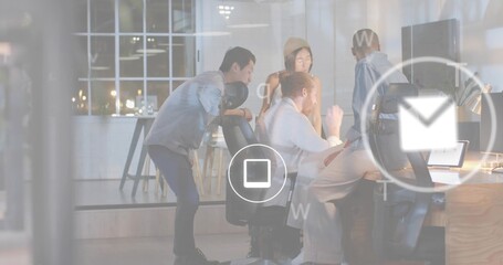 Leaning coworkers wearing casual attire and beanie viewing laptop at office, showing UI icons