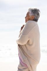 Side view of senior woman with short white hair wearing shrug at beach on sunny day