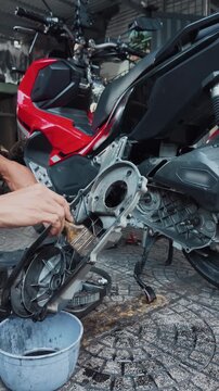 worker performs maintenance at vehicle repair station, man cleanse motorcycle or scooter variator automatic gearbox, mechanic cleaning car gear box, 4k vertical video