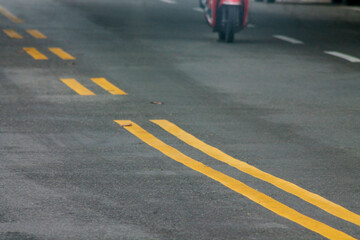 Yellow Lines on a Winding Road. Abstract turning road background with tires track and yellow striped road marking on dark asphalt.