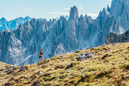 Woman trail running through majestic mountain landscape on a sunny day