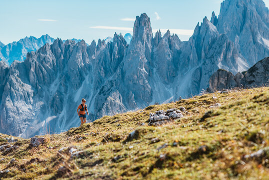 Woman trail running through majestic mountain landscape on a sunny day