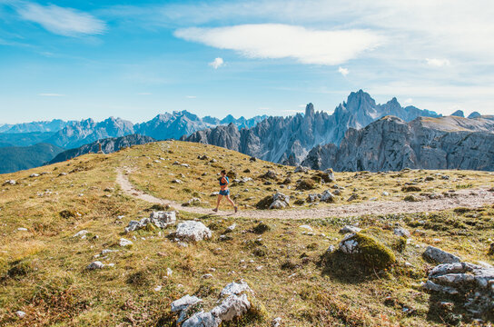 Woman trail running through scenic mountain landscape with rocky peaks