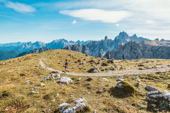 Woman trail running through scenic mountain landscape with rocky peaks