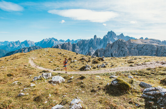 Woman trail running through scenic mountain landscape with rocky peaks