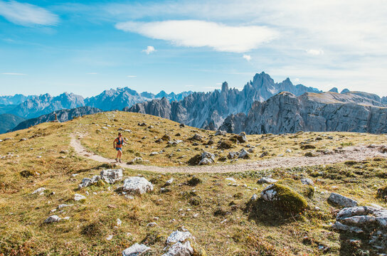 Woman trail running through scenic mountain landscape with rocky peaks