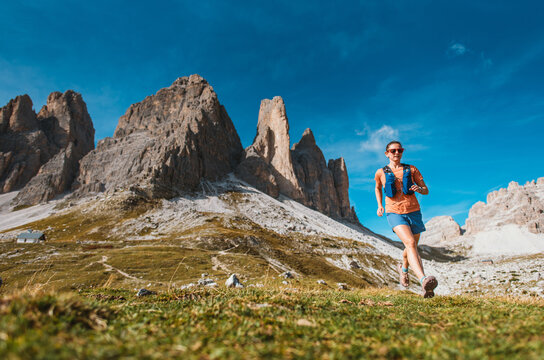 Woman trail running through the Dolomites mountains on a sunny day