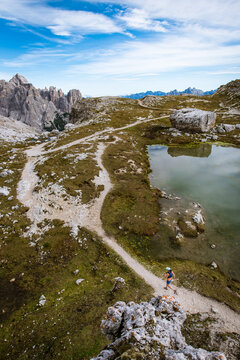 Woman trail running beside a mountain lake with dramatic peaks