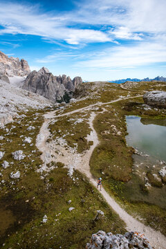Woman trail running beside a mountain lake with dramatic peaks