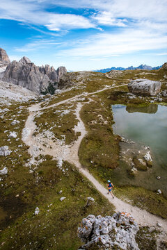 Woman trail running beside a mountain lake with dramatic peaks