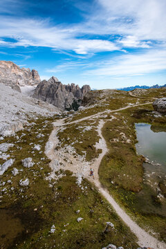Woman trail running beside a mountain lake with dramatic peaks