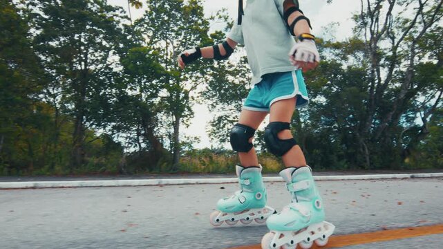 Girl learns roller skating on the road in the park and does her first attempts in the sport