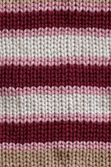Close-up of a knitted fabric showcasing horizontal stripes in various warm colors, ideal for texture and design inspiration.